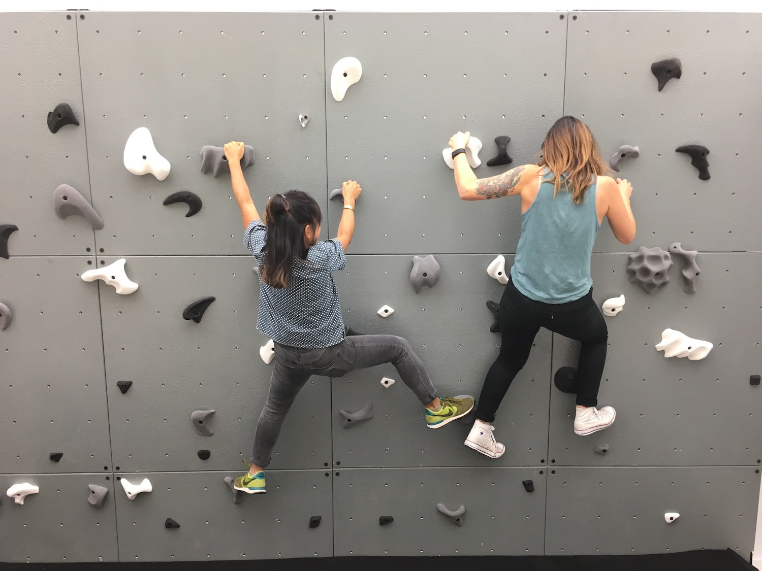 Mom and kid climbing on a home climbing wall