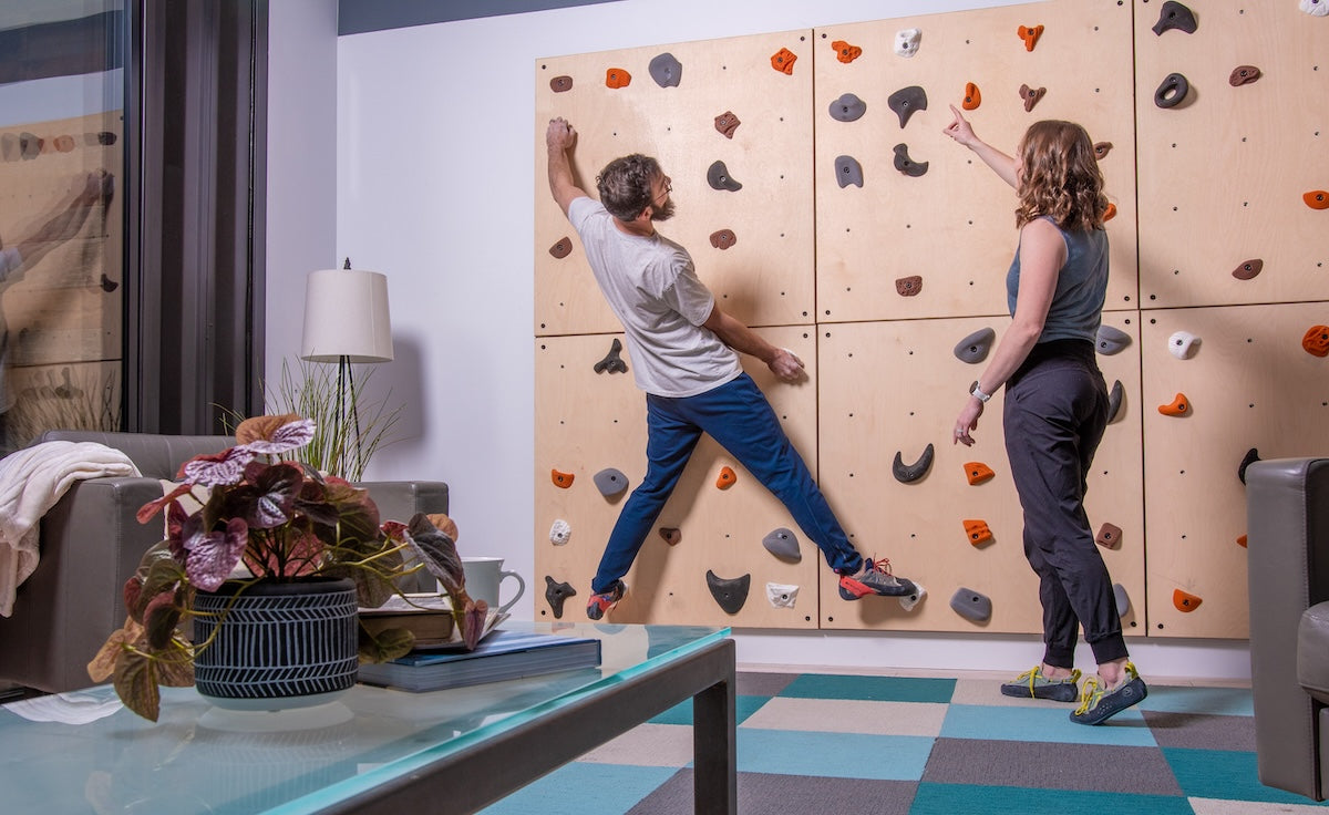 man & woman climbing on a home climbing wall