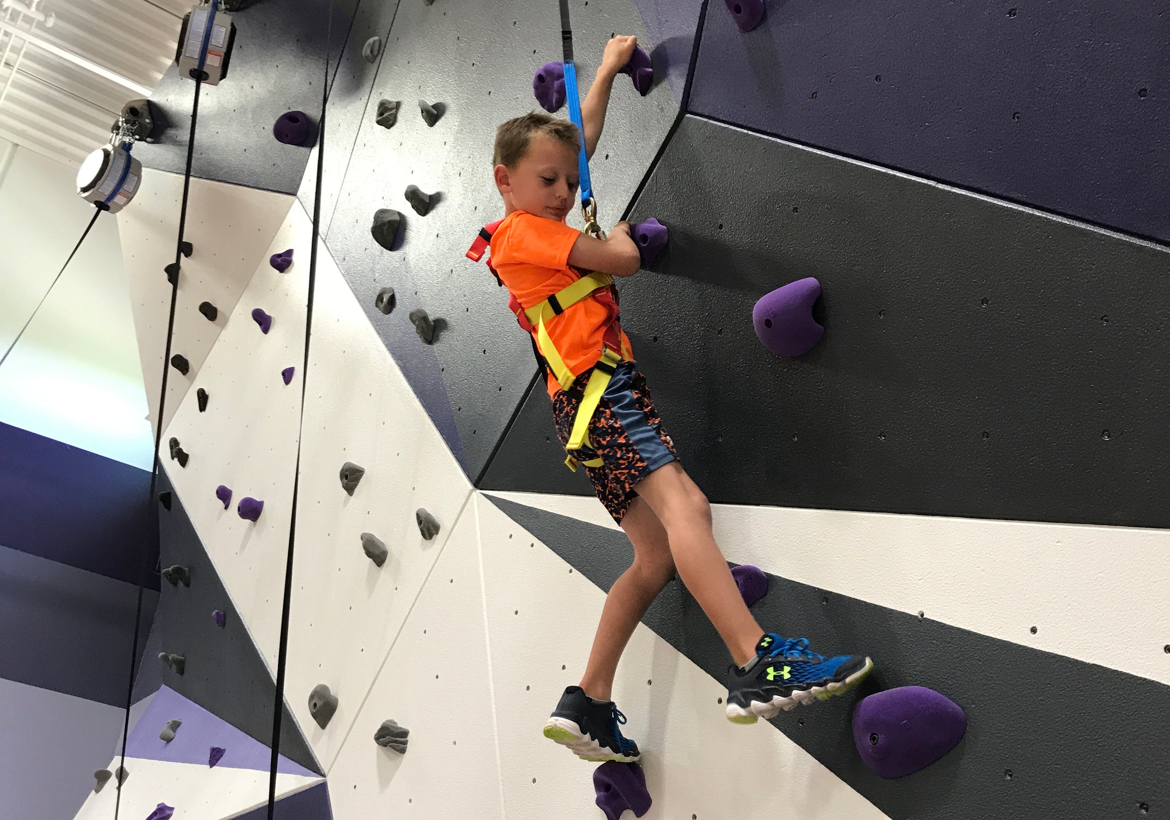 Boy tries sport climbing on the rock climbing wall in his school gym