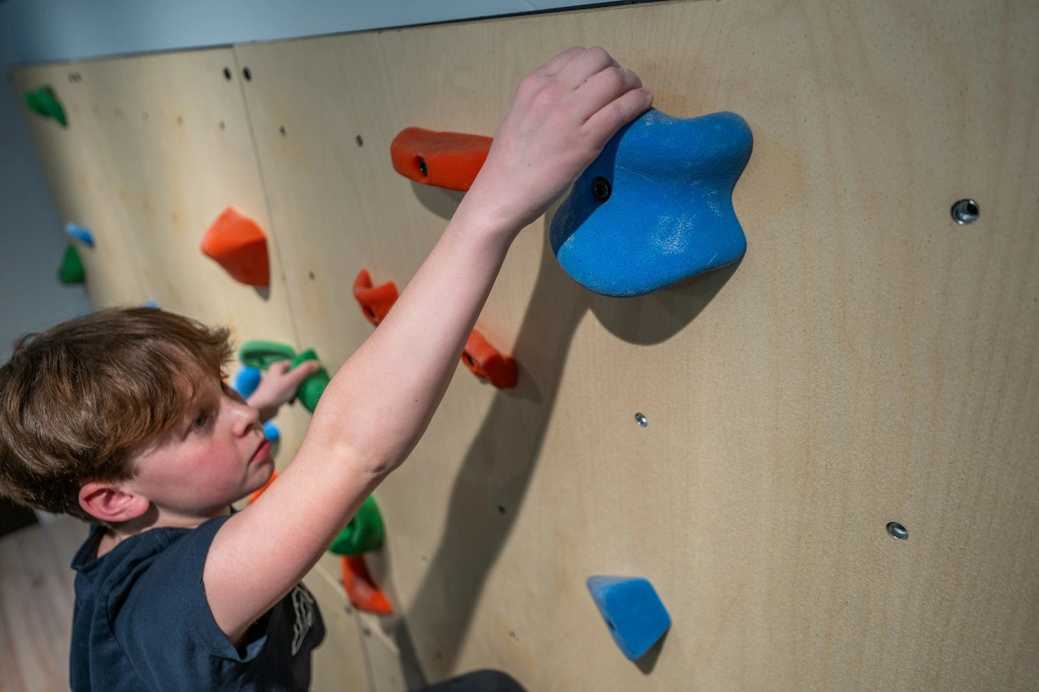 Kid climbing at home reaching for a hold