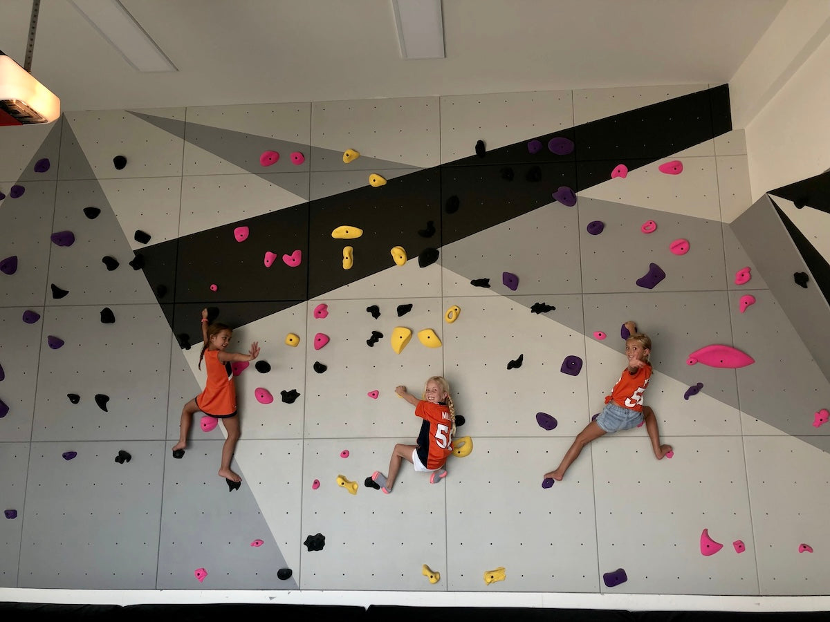 three kids climbing on a home climbing wall