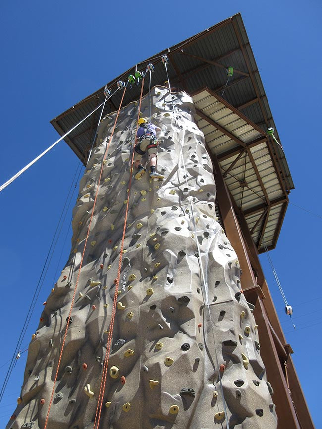 Child learns to sport climb on a top rope climbing tower.
